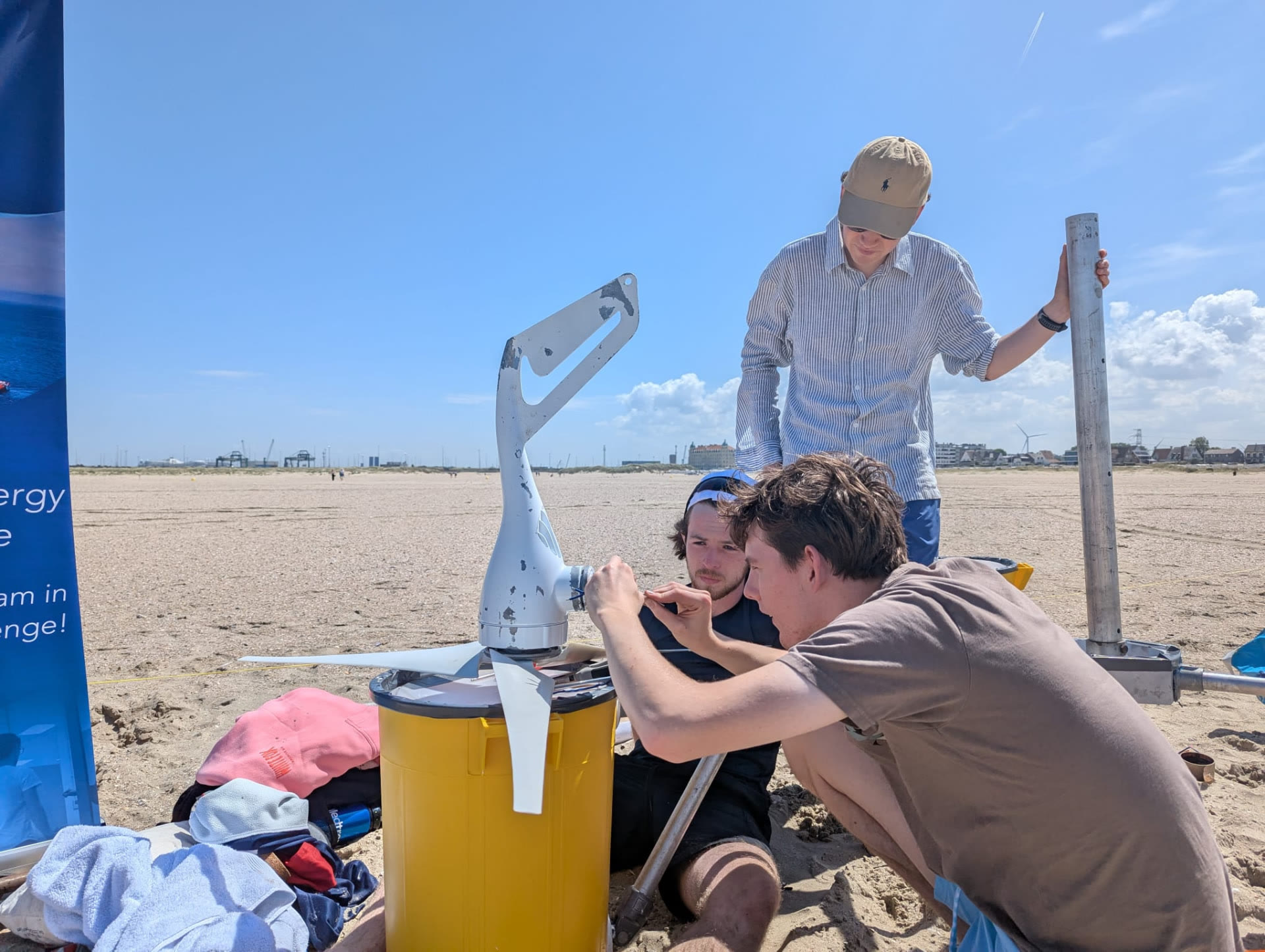 Team members repairing the small wind turbine on the beach